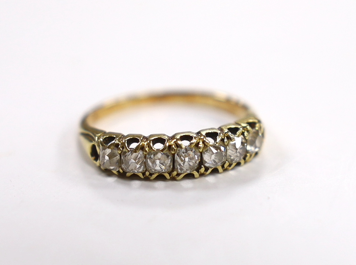 A yellow metal and seven stone diamond set half hoop ring, size N/O, gross weight 3.1 grams.
